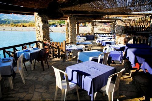 Un restaurante con mesas y sillas con vista a un cuerpo de agua.