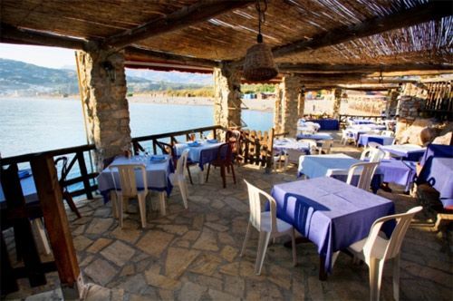Un restaurante con mesas y sillas con vista al mar.