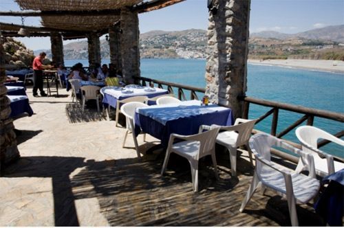 Un restaurante con mesas y sillas con vista al mar.