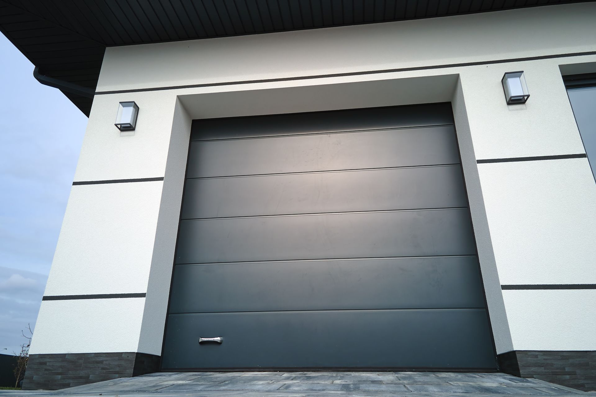 Porte de garage grise moderne sur une façade de maison blanche