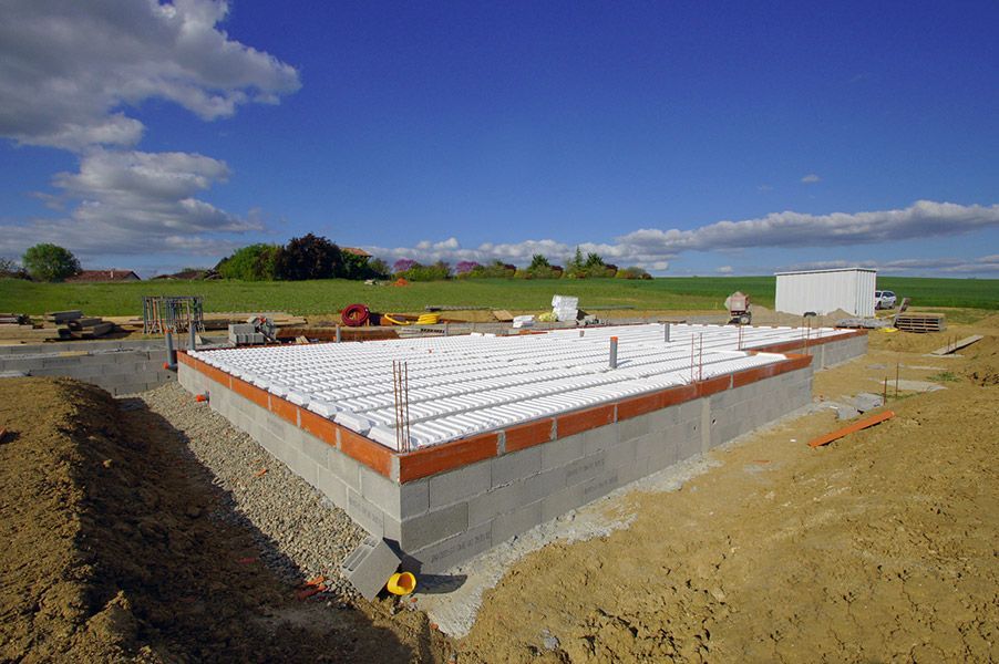 Fondations d'une maison neuve en construction, panneaux isolants blancs et ciel ouvert au-dessus