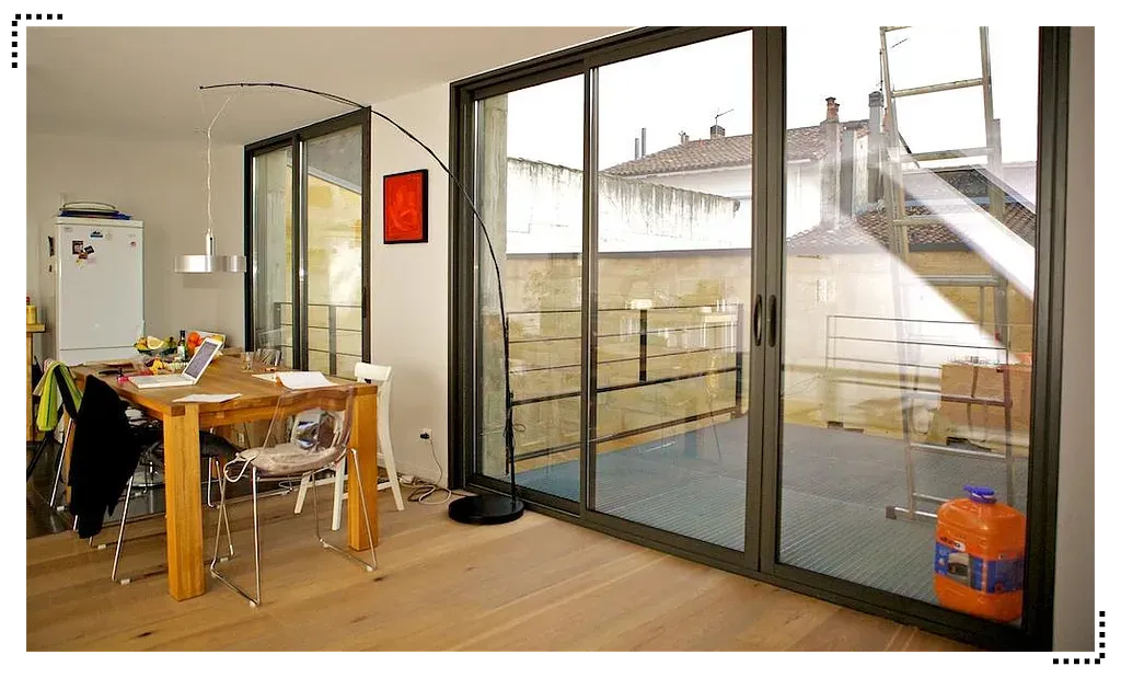 Salle à manger moderne et ouverte avec de grandes portes vitrées donnant sur un balcon