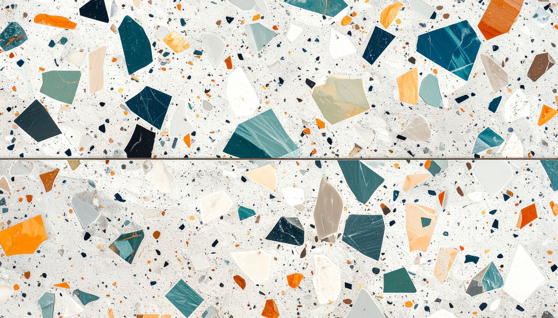 Surface blanche de style terrazzo avec des éclats de pierre épars turquoise, orange et gris.