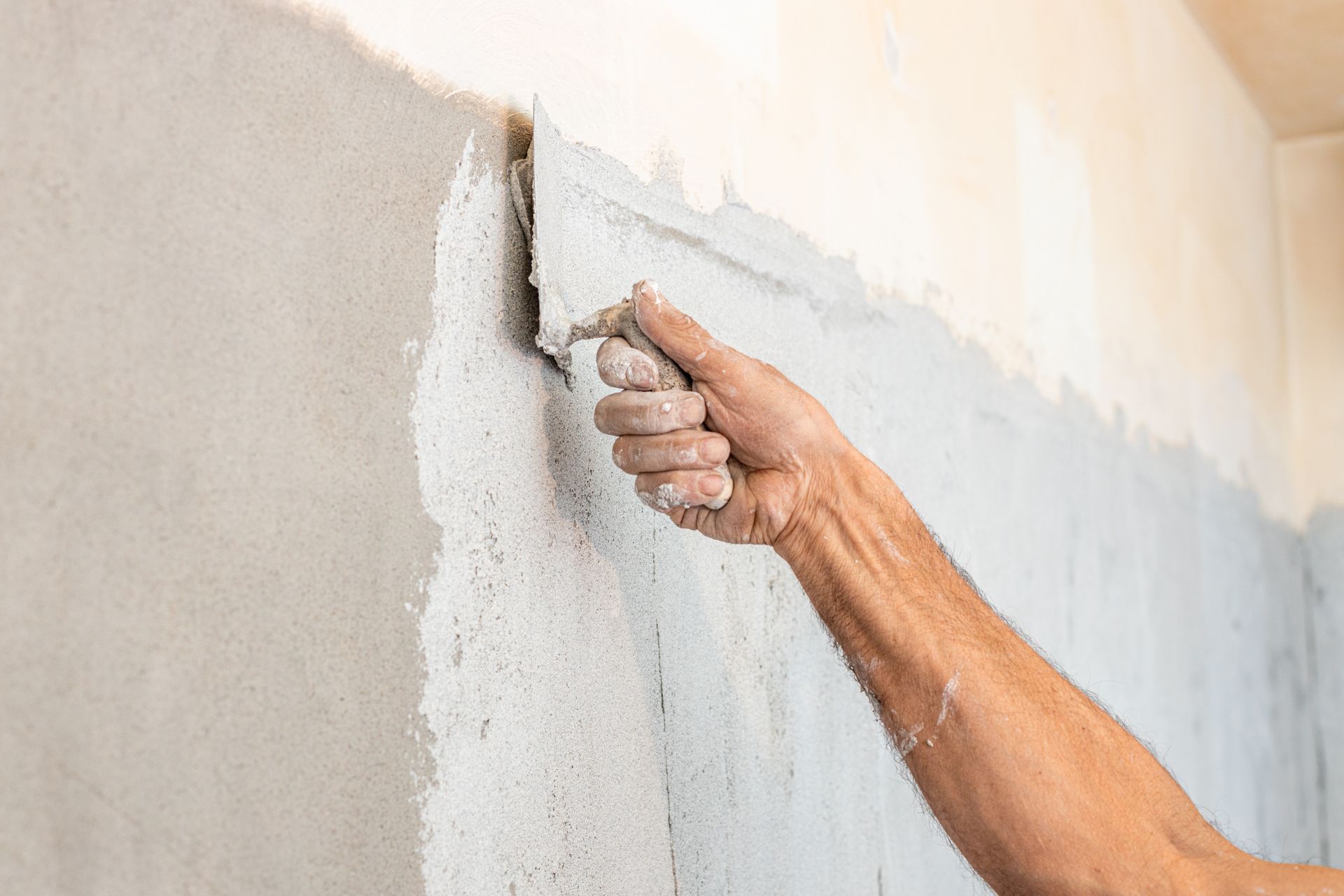 Lissage manuel du plâtre humide sur un mur lors de réparations intérieures.