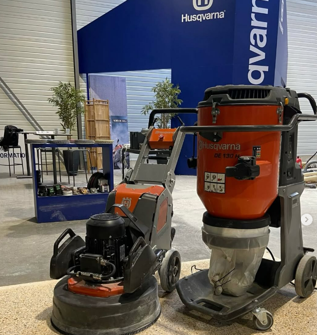 Des ponceuses à parquet Husqvarna sont exposées sur un stand lors d'un salon professionnel en intérieur.