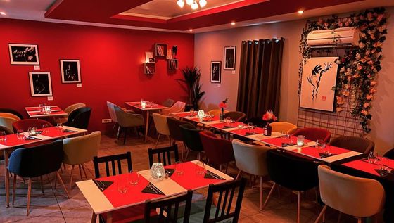 Salle de restaurant à l'ambiance tamisée, avec des bougies sur les tables et les rideaux de fenêtre fermés.