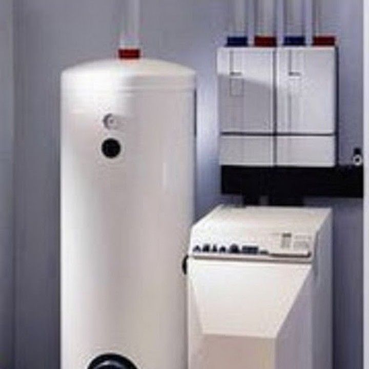 Calentador de agua blanco, panel de control adyacente y sistema de calefacción en un espacio cerrado.