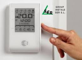 Mano presionando un termostato que marca 20 grados Celsius. Logotipo 