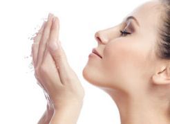 Una mujer con casco sonríe, con paneles solares y turbinas eólicas en el fondo.