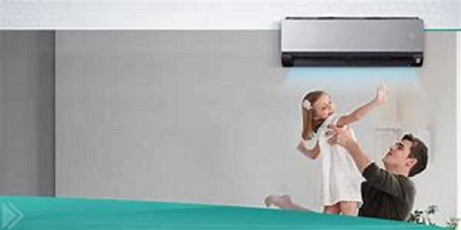 Un hombre y un niño disfrutan del aire acondicionado. Están de pie frente a una pared gris.