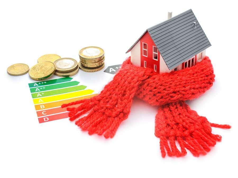 Pequeña casa envuelta en un pañuelo rojo, con monedas y un cuadro de clasificación de eficiencia energética.