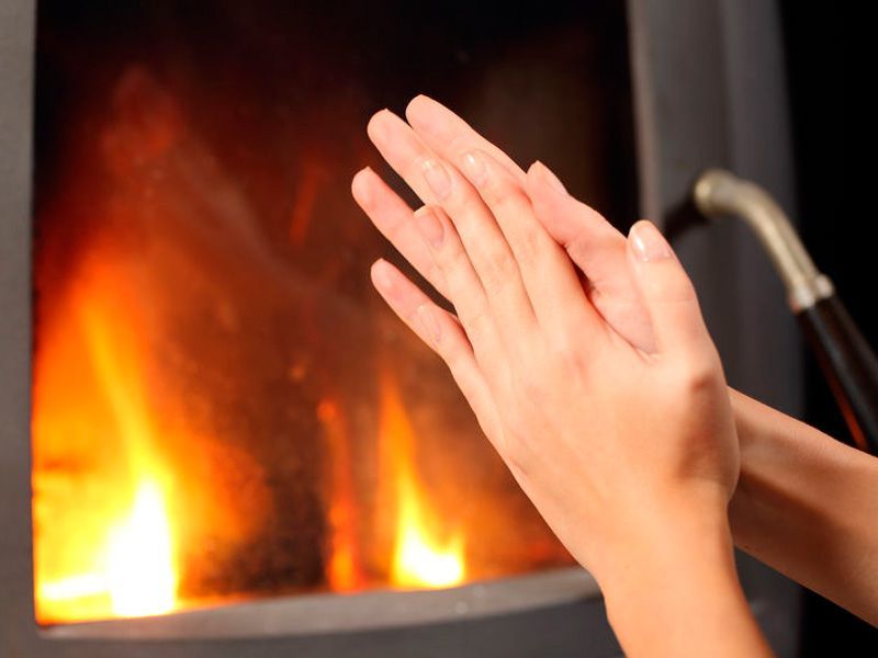 Manos calentándose junto a una chimenea, llamas visibles.