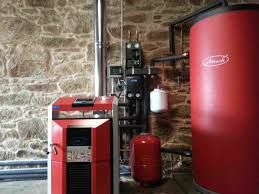 Estufa de pellets rojos y tanque en una habitación con paredes de piedra.