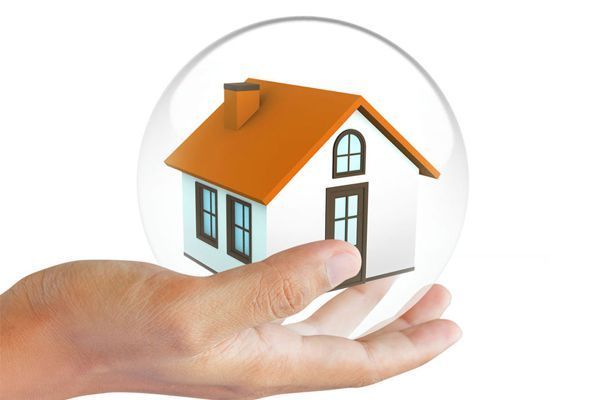 Mano sosteniendo una casa en miniatura encerrada en una burbuja transparente.