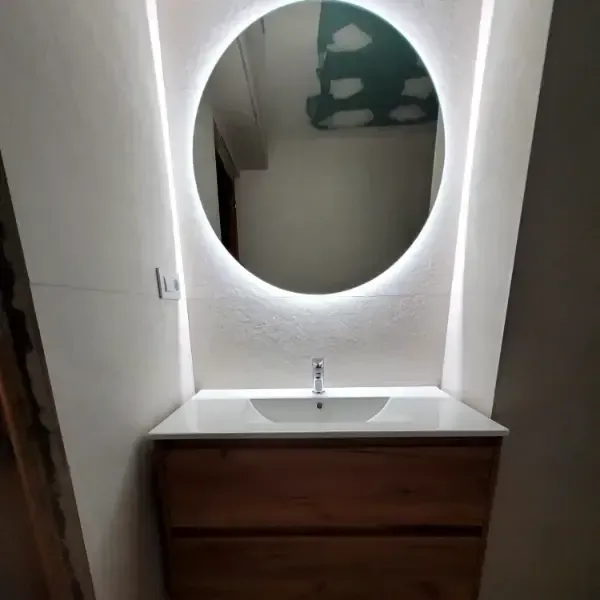 espejo redondo instalado con luces sobre pared blanca