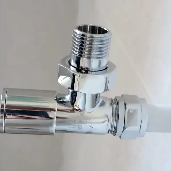 Válvula de radiador cromada brillante conectada a un tubo de plástico blanco. La válvula está roscada para radiador.