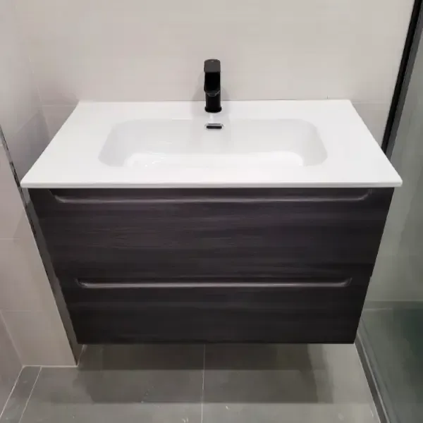 Tocador de baño flotante de veta de madera oscura con encimera blanca y grifo negro.