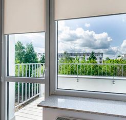 Una ventana con persianas y vista a un balcón.
