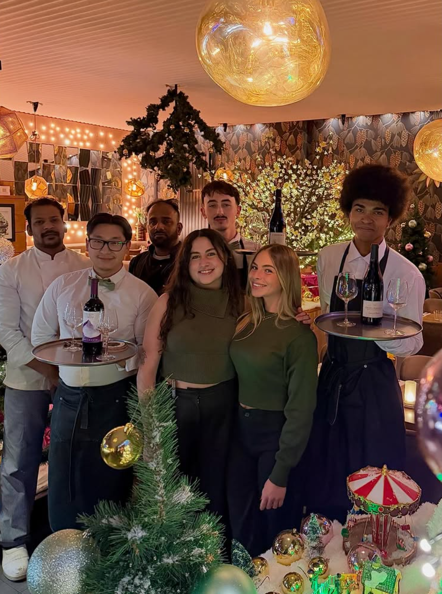 Un morceau de gâteau triangulaire garni de glaçage à la poche à douille et de pistaches concassées, arrosé de caramel et présenté sur une ardoise.