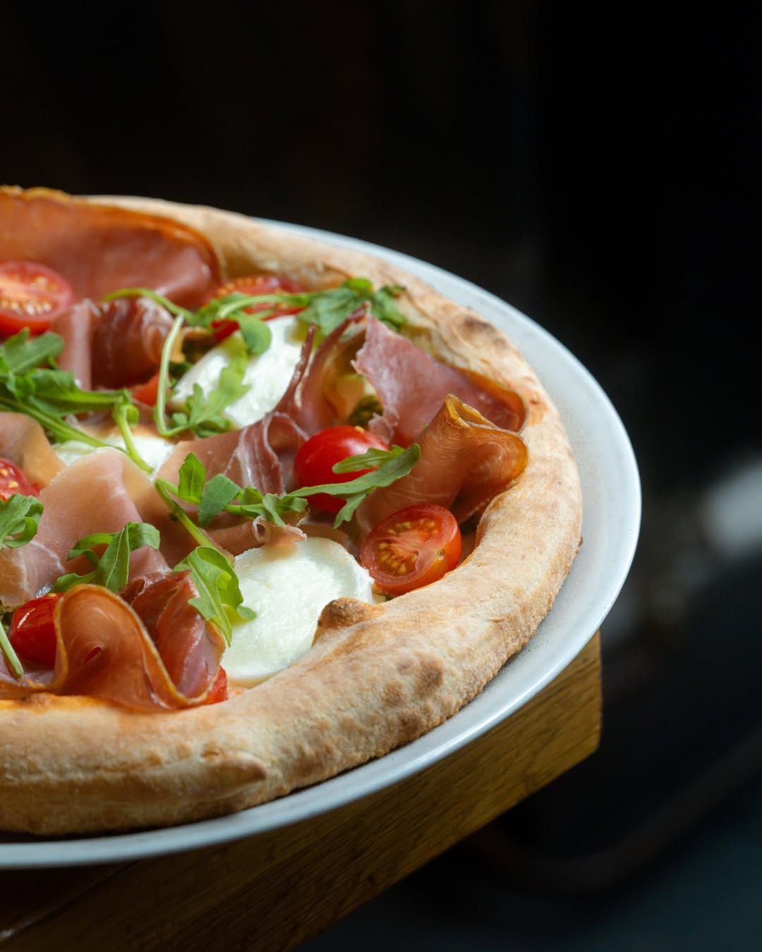 Une pizza garnie de prosciutto, de mozzarella
