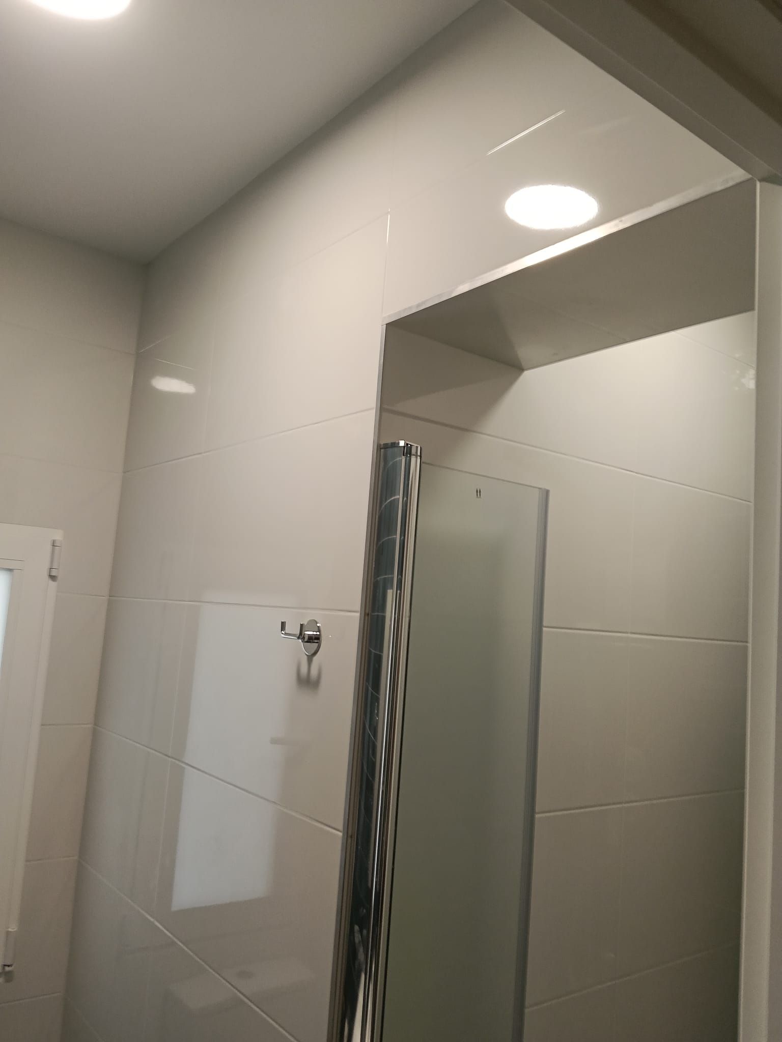 Baño moderno con paredes revestidas de azulejos grises, espejo y mampara de ducha cromada