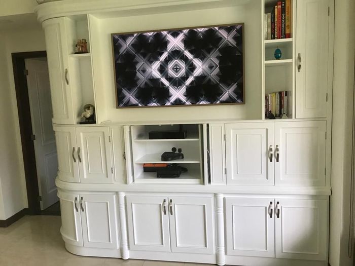 Mueble empotrado blanco para el salón, con televisor, armarios, estantes y un pequeño nicho central.