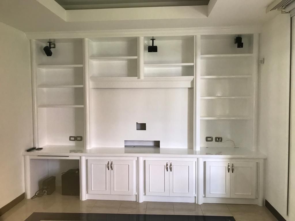 Armarios empotrados y estantes blancos alrededor de un hueco central para el televisor en un salón luminoso