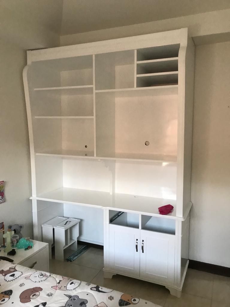 Estanterías y armarios empotrados blancos en una habitación, con espacio de almacenamiento abierto y una pequeña zona de escritorio.