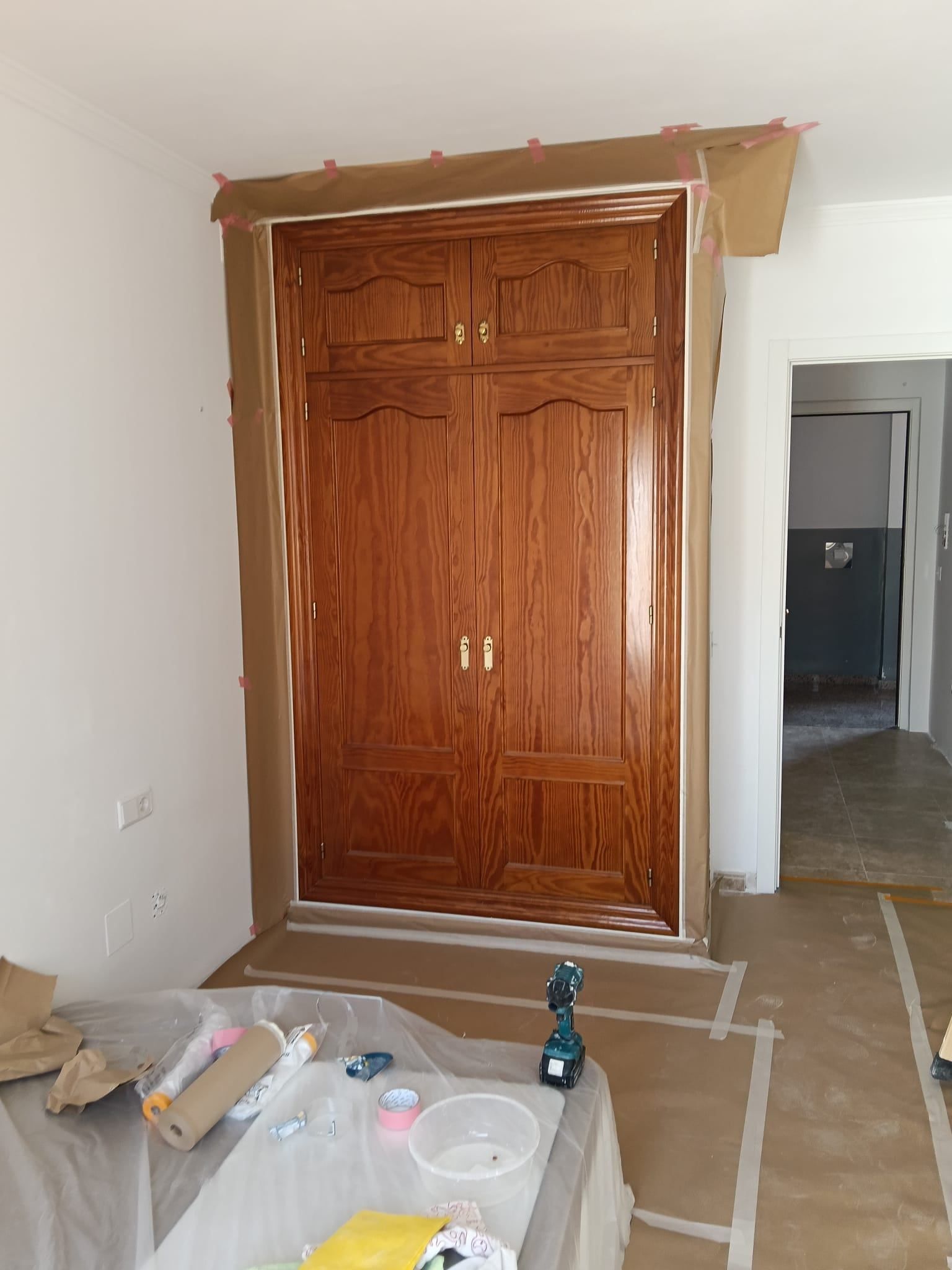 Entrada parcialmente terminada, con una puerta de armario de madera y materiales de construcción en el suelo