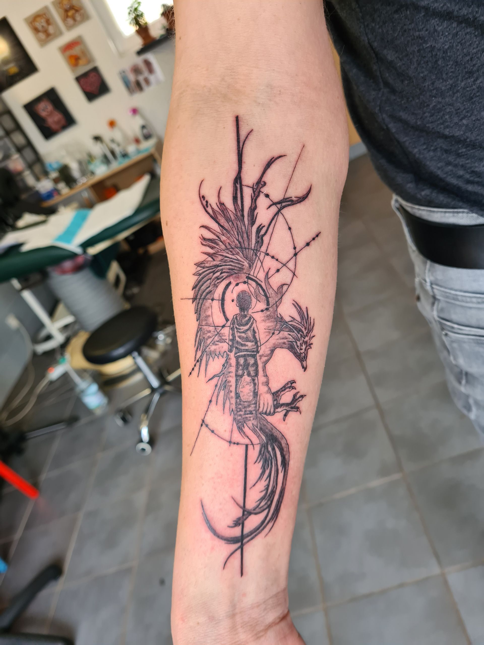 Tatouage d'un dragon noir sur l'avant-bras, intégrant des lignes et des motifs géométriques. 