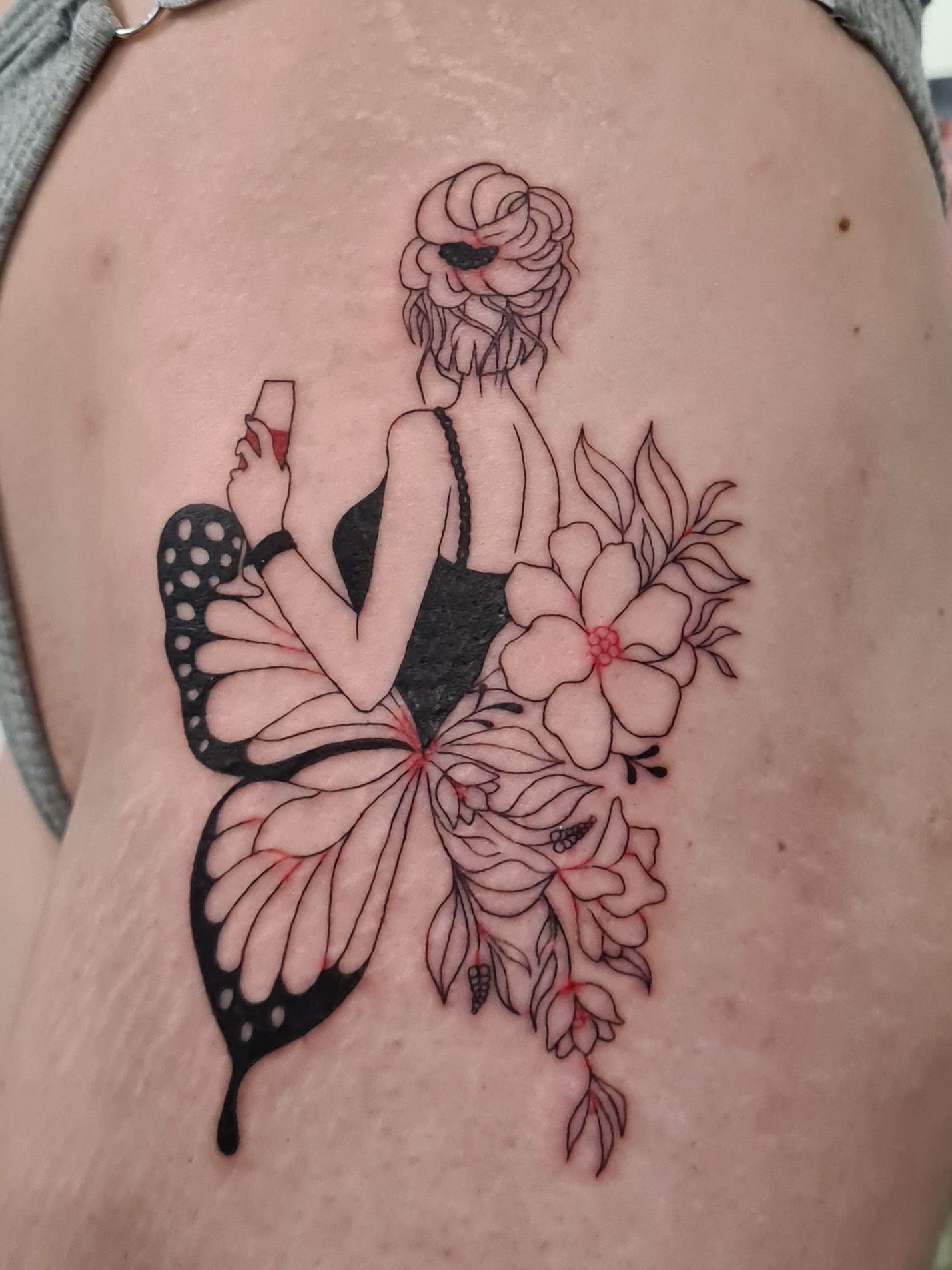 Tatouage d'une femme aux ailes de papillon, tenant un verre.