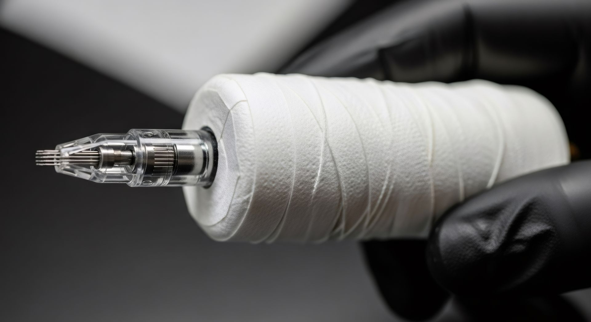 Gros plan sur une machine à tatouer noire sur fond sombre.