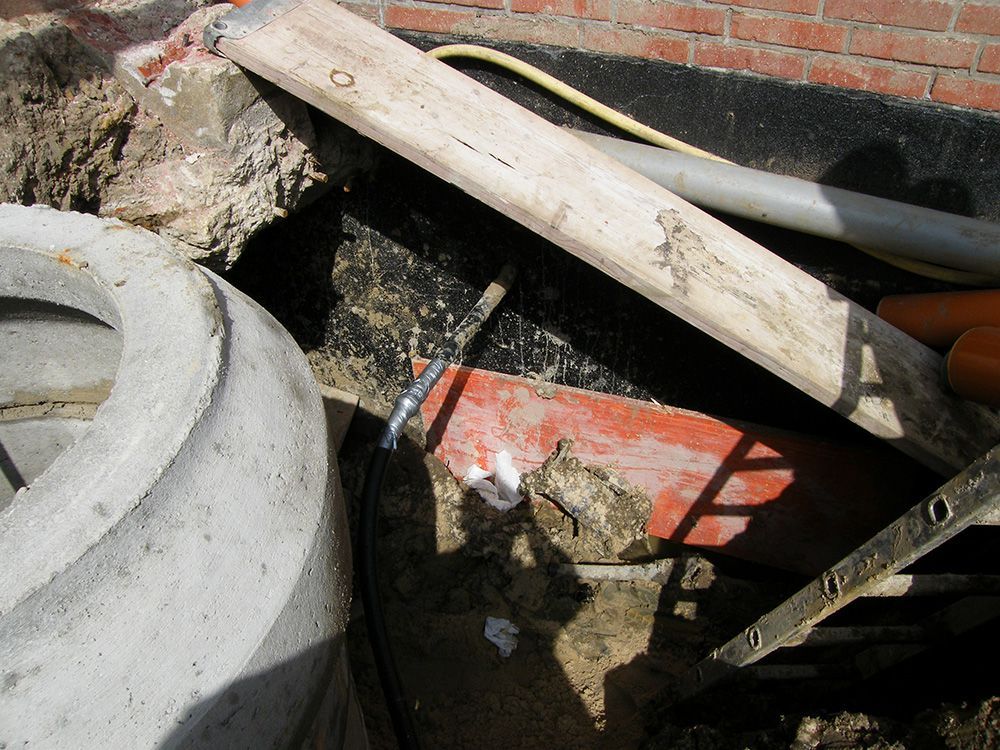 Ein Holzbrett liegt auf dem Boden neben einem Betonrohr