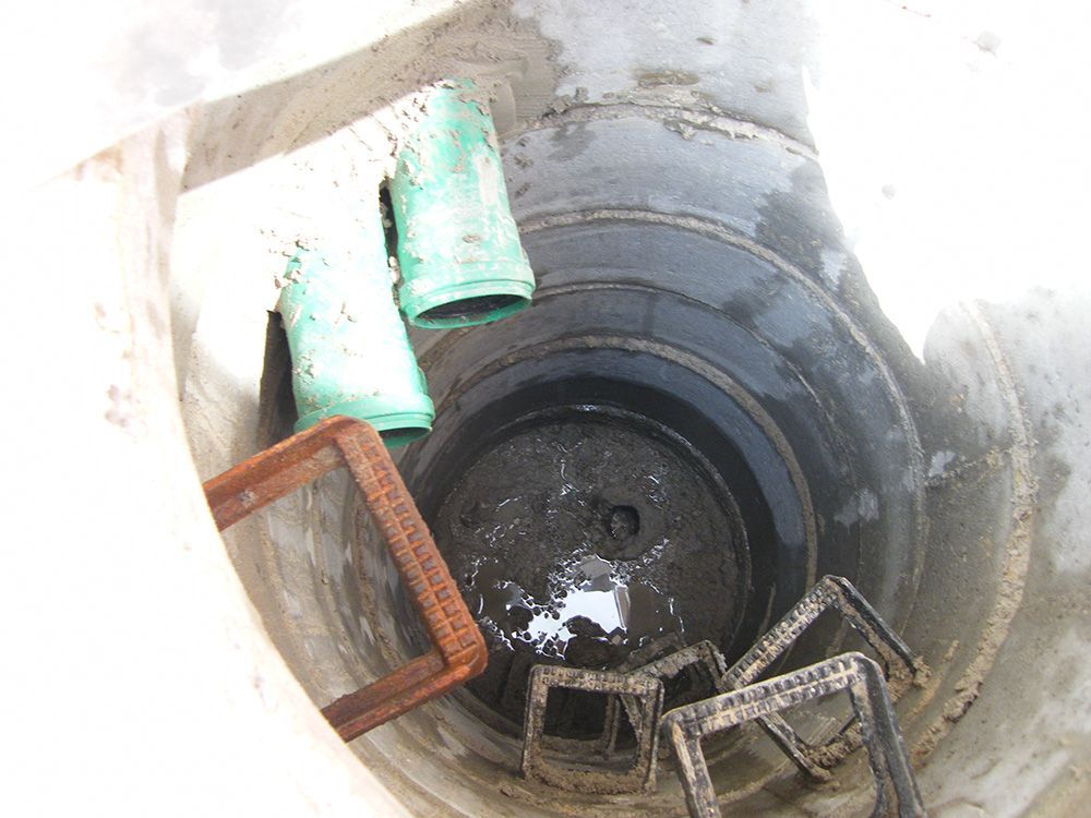 Ein Loch im Boden mit einer Leiter und Rohren darin.