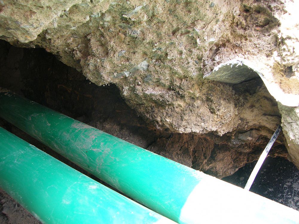 Ein grünes Rohr ragt aus einem Loch im Boden.