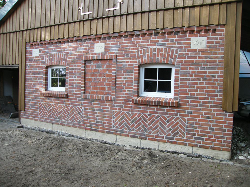 Ein rotes Backsteingebäude mit weißen Fenstern und einem Holzdach