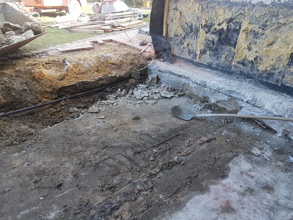 Neben einem im Bau befindlichen Gebäude liegt eine Schaufel auf dem Boden.