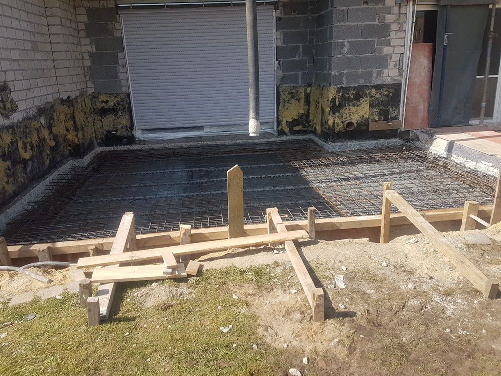 Vor einem Backsteingebäude wird ein Betonboden gebaut.