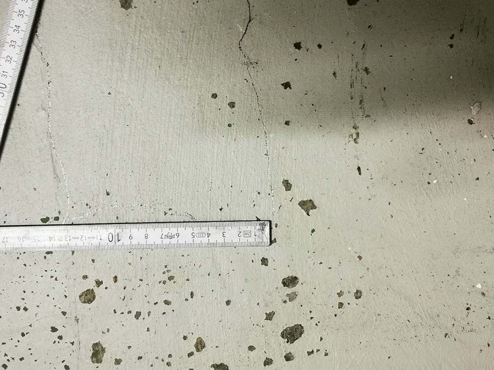 Ein Lineal liegt auf einem schmutzigen Betonboden.