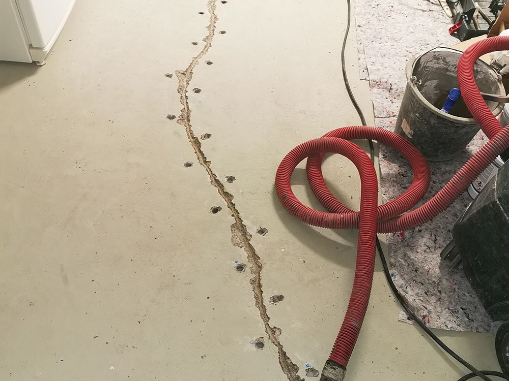 Ein roter Schlauch liegt neben einem Staubsauger auf dem Boden.