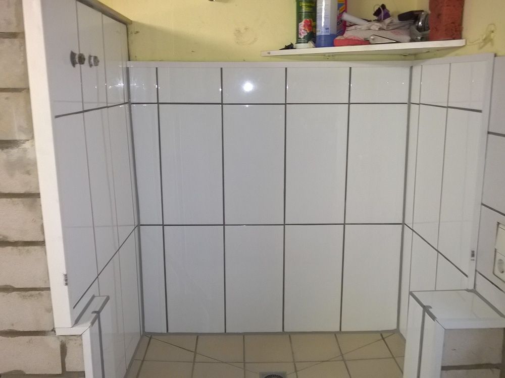 Ein Badezimmer mit weißen Fliesen und einem Regal an der Wand