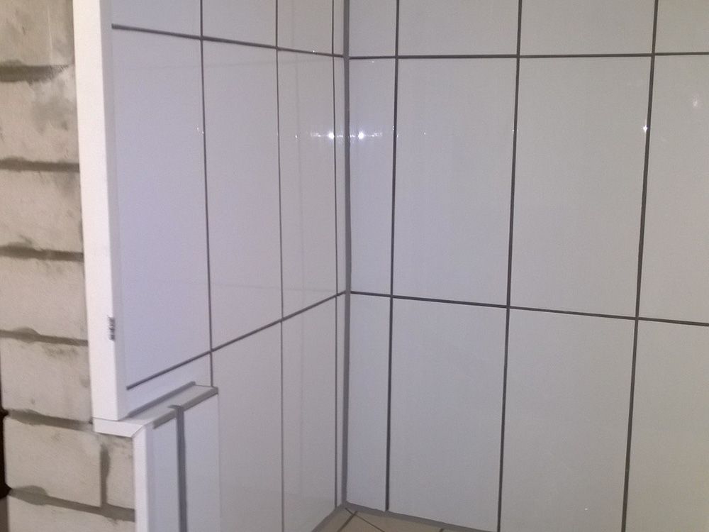 Eine Badezimmerecke mit weißen Fliesen an der Wand