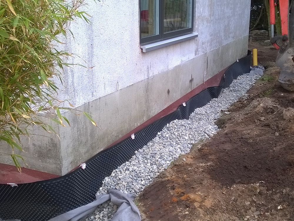 An der Seite eines Hauses wird ein Entwässerungssystem installiert