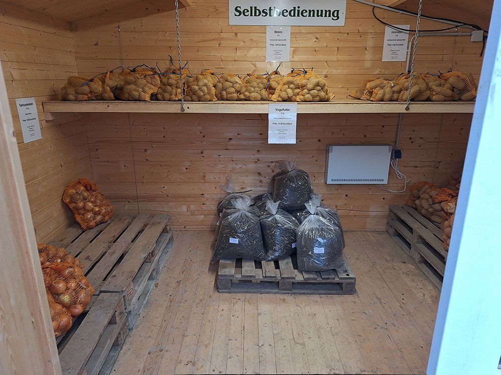 Ein Holzschuppen voller Säcke mit Kartoffeln und Zwiebeln