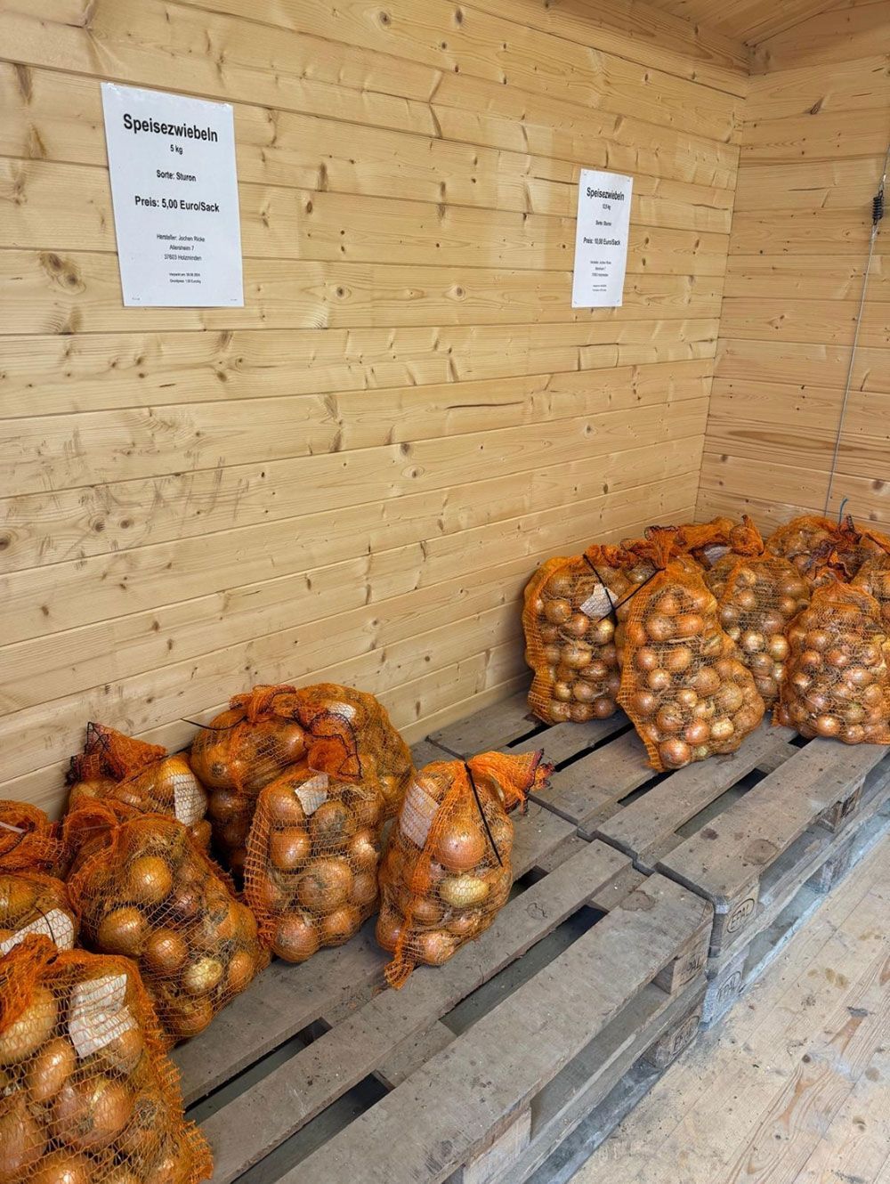 Auf einem Holzregal stehen mehrere Säcke mit Zwiebeln.