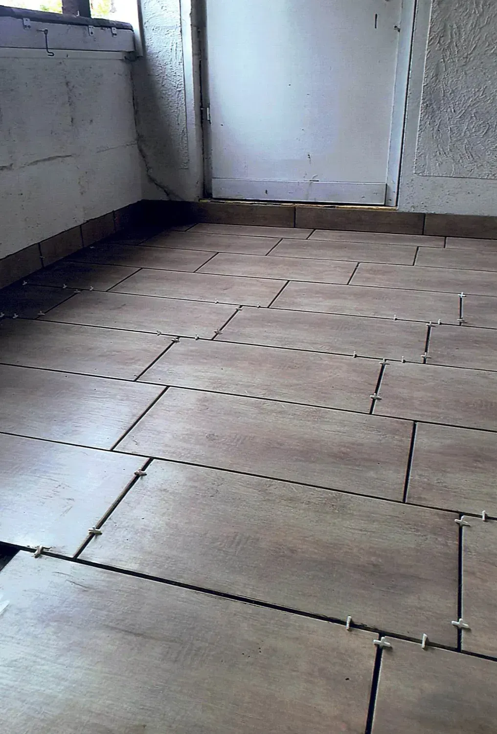 Ein Raum mit gefliestem Boden und einem Fenster.