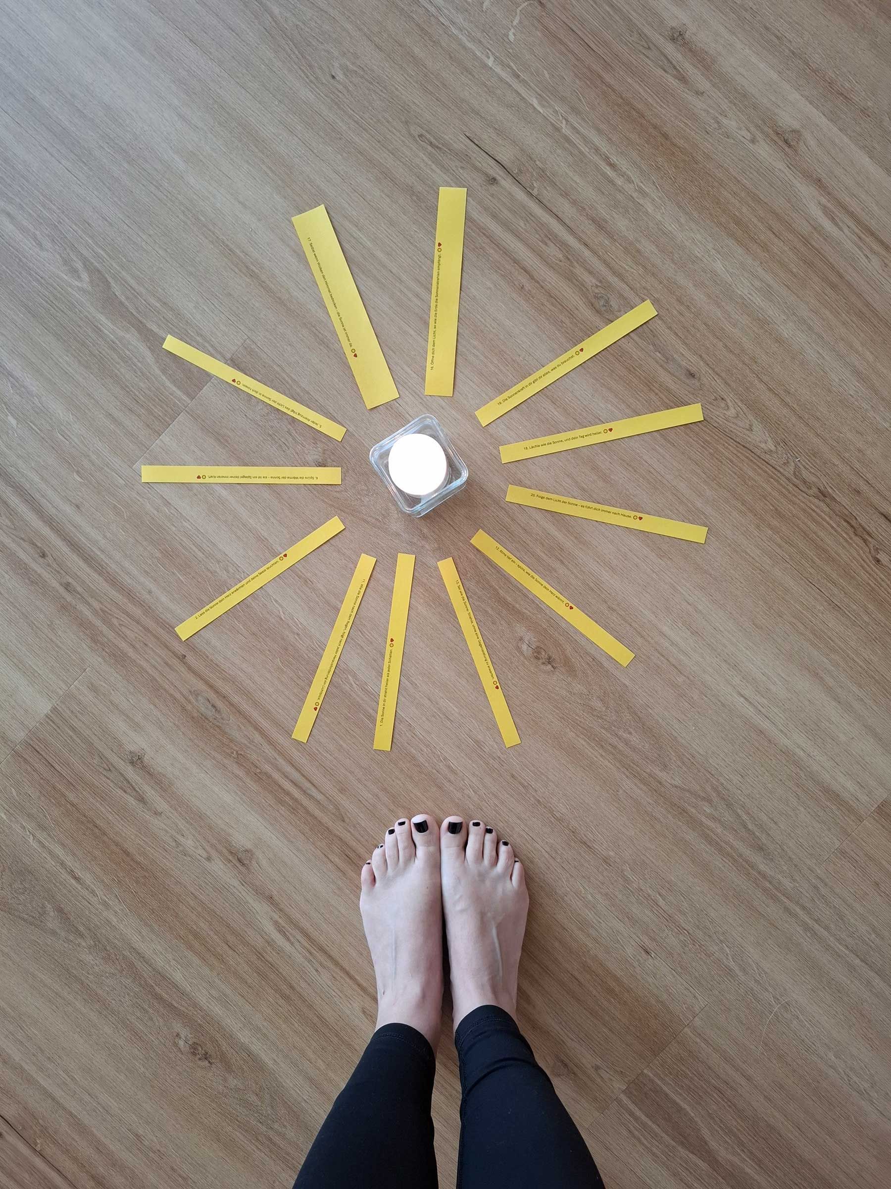 Die Füße einer Person stehen vor einer gelben Sonne, die auf den Boden gezeichnet ist.