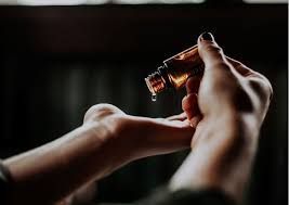 Eine Person gießt ätherisches Öl in ihre Hand.