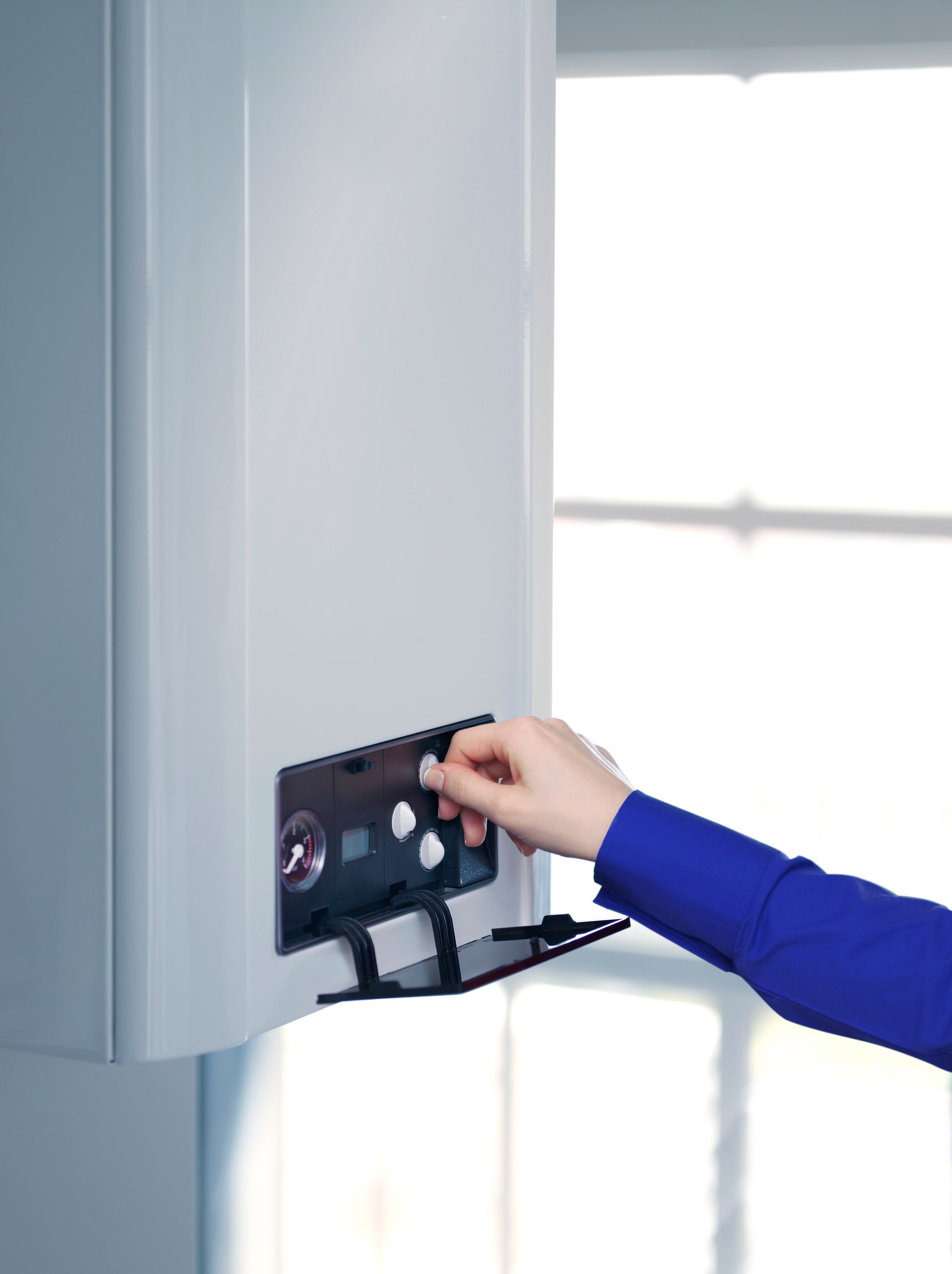 Una persona está presionando un botón en una caldera.