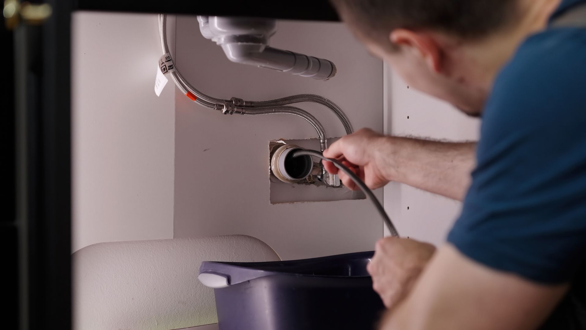 Un plombier utilise un furet pour déboucher une canalisation.